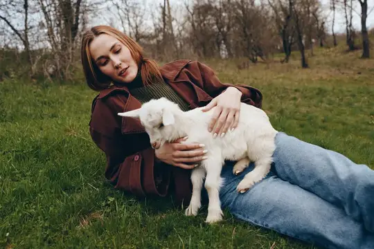 Нежный момент: женщина отдыхает с козлёнком на свежем воздухе