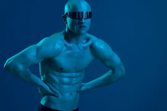 Мускулистый лысый мужчина в футуристических очках позирует в синем свете