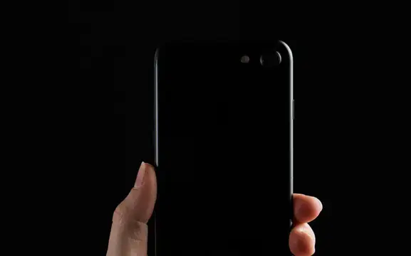 Рука держит смартфон с двойной камерой на чёрном фоне