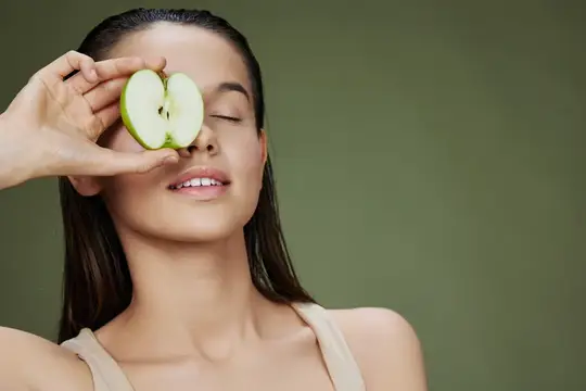 Женщина с зелёным яблоком улыбается