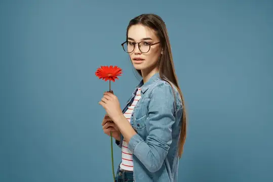 Молодая женщина в очках с красным цветком на синем фоне