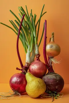 Красный лук, зелёные перья и спелая груша на оранжевом фоне