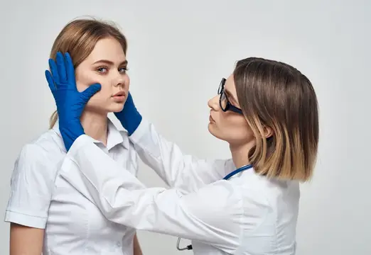 Женщина-врач в медицинском халате и синих перчатках, с фонендоскопом на шее, и пациентка