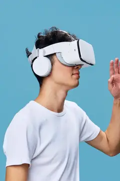Молодой азиатский парень в VR-очках и наушниках на голубом фоне