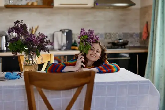 Улыбчивая девочка с веткой сирени за кухонным столом