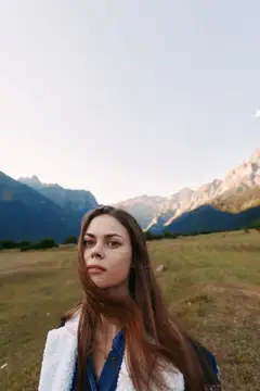 Молодая женщина с длинными волосами на фоне горного пейзажа