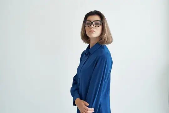 Молодая женщина в очках и синей рубашке на белом фоне