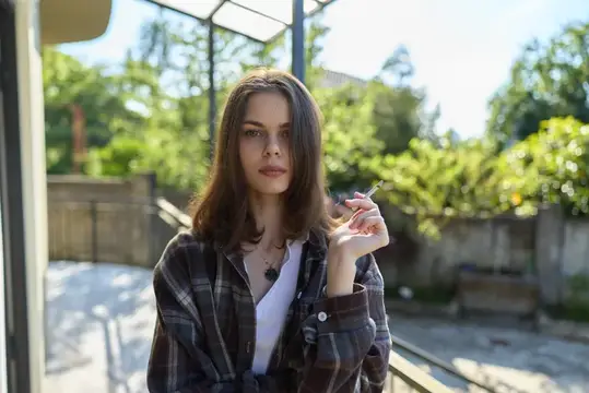 Молодая шатенка с сигаретой на летней террасе