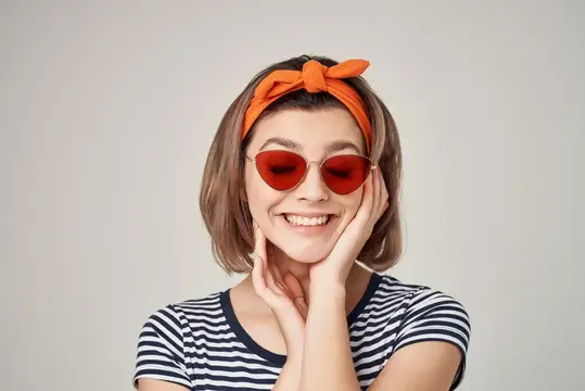 Женщина в полосатой футболке и солнцезащитных очках, с повязкой на голове, на светлом фоне