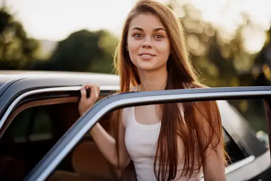 Молодая женщина с длинными волосами выглядывает из окна автомобиля
