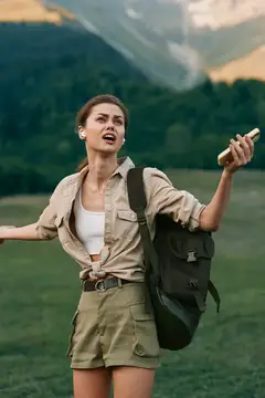 Девушка с рюкзаком ловит связь на фоне гор