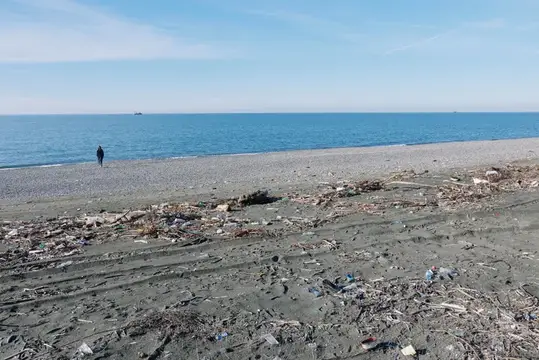 Одинокий человек на пустом пляже с мусором у моря