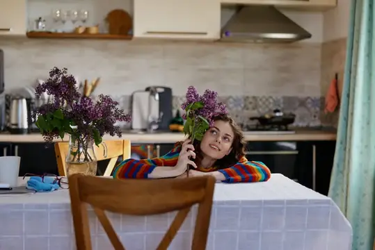 Девочка с ветками сирени за столом на кухне