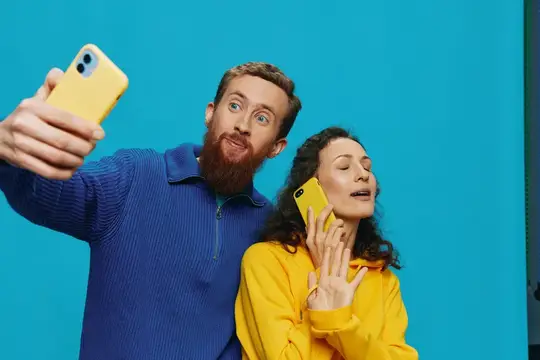 Бородатый мужчина и женщина с телефонами на синем фоне