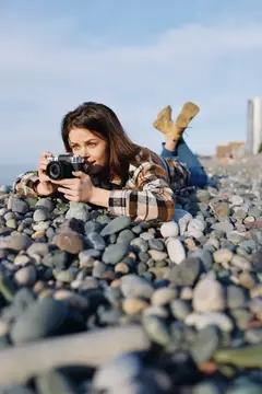 Девушка лежит на каменистом пляже и фотографирует