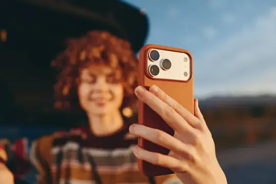 Рыжеволосая девушка фотографирует на смартфон в сумерках