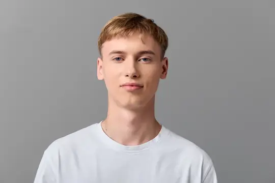 Молодой блондин в белой футболке на сером фоне