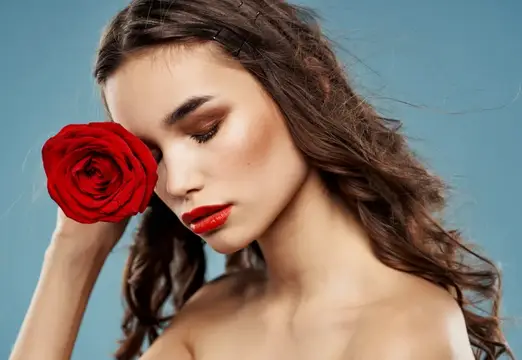 Сексуальная женщина с обнаженными плечами и красным цветком возле лица