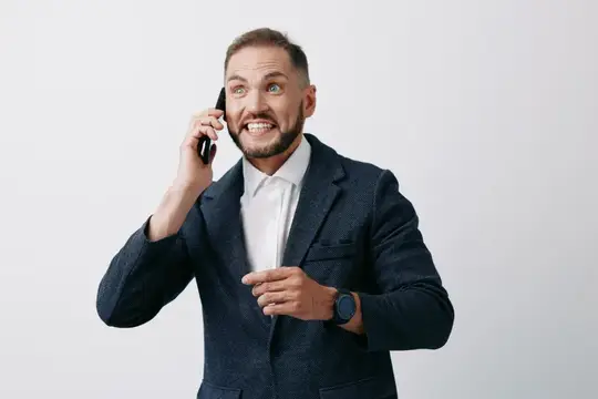 Удивлённый бородатый мужчина в пиджаке говорит по телефону