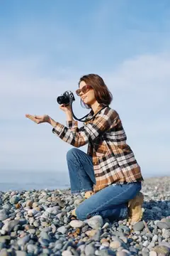 Девушка с фотокамерой на галечном пляже