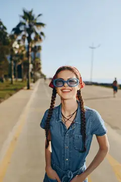 Улыбчивая девушка с двумя косами и в солнечных очках на набережной