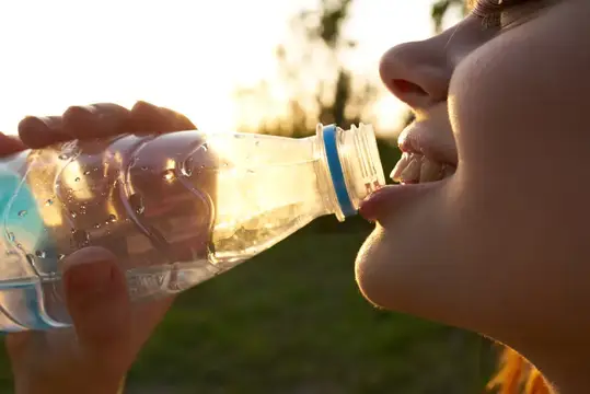 Девушка пьёт воду из бутылки на закате