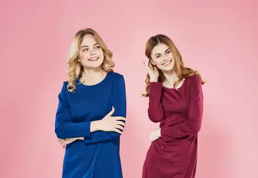 Две элегантные женщины общаются в студии на розовом фоне, демонстрируя стиль жизни и дружеские отношения