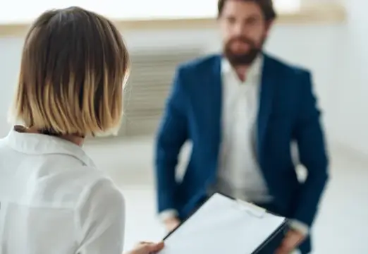 Женщина с планшетом на деловой встрече с бородатым мужчиной в костюме