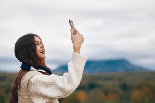 Улыбающаяся девушка делает селфи на фоне гор