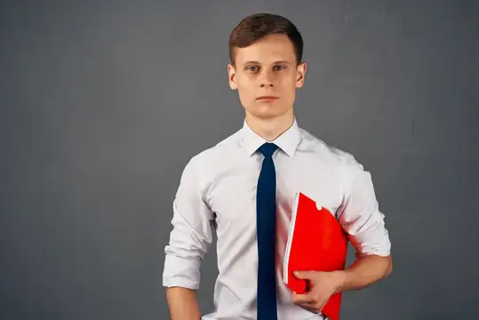 Молодой человек в белой рубашке с красной папкой на сером фоне
