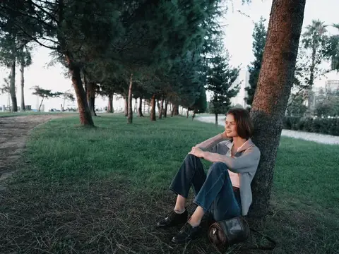 Молодая женщина отдыхает под сосной в парке