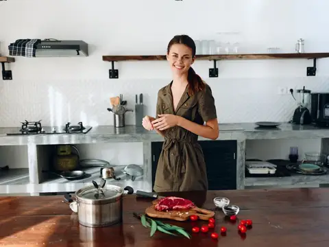 Улыбающаяся девушка готовит ужин на светлой кухне