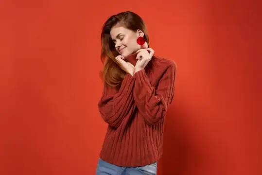 Улыбающаяся девушка в красном свитере на красном фоне