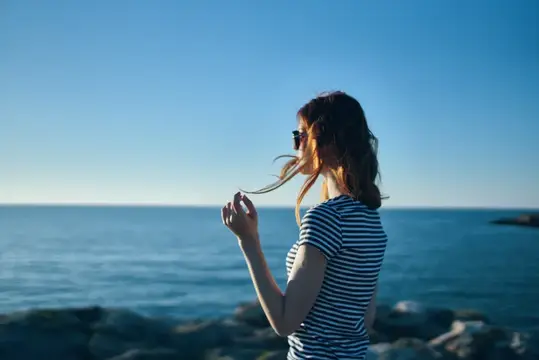 Женщина на пляже в горах у моря на закате, лето, обрезанный вид
