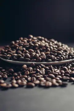 Горка обжаренных кофейных зёрен рассыпана на тёмной поверхности