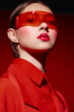 Молодая женщина в красных очках и рубашке на красном фоне