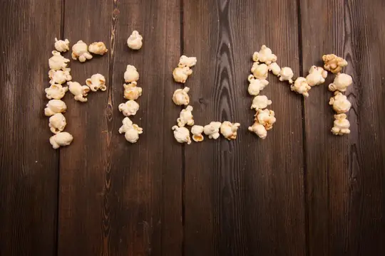 Попкорн выложен в виде слова «movie» на деревянном фоне — закуска