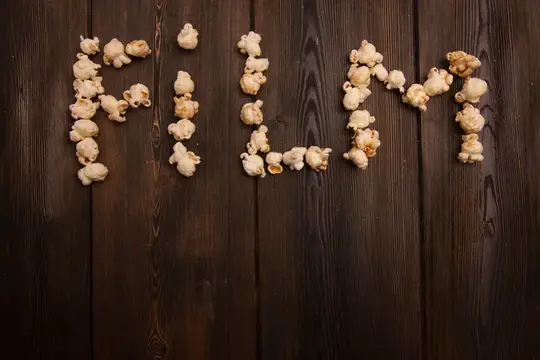 Слово POPCORN, выложенное попкорном на тёмном дереве