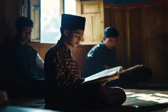 Молодой человек в тюбетейке читает книгу в деревянной комнате