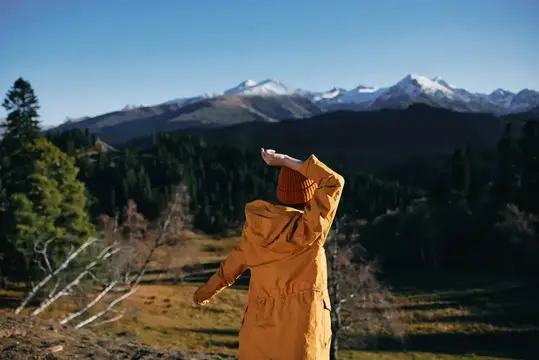 Человек в жёлтой куртке любуется заснеженными горами