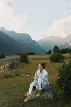 Молодая женщина отдыхает на лугу с видом на горы