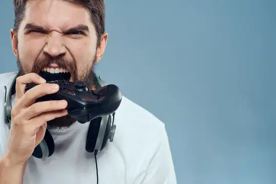Разъяренный бородатый геймер кусает игровой контроллер