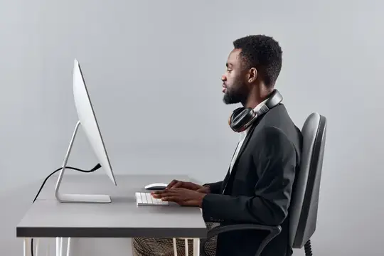 Темнокожий мужчина в наушниках работает за компьютером