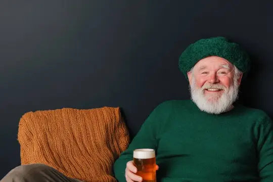 Улыбчивый седобородый мужчина в зелёном берете с бокалом пива