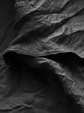 Крупный план двух слоев черной ткани на столе, демонстрирующий текстуру и контраст
