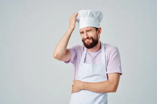 Шеф-повар в униформе жестикулирует руками, выражая эмоции во время работы в ресторане