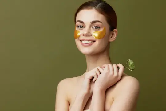Улыбающаяся девушка с золотыми патчами под глазами на оливковом фоне