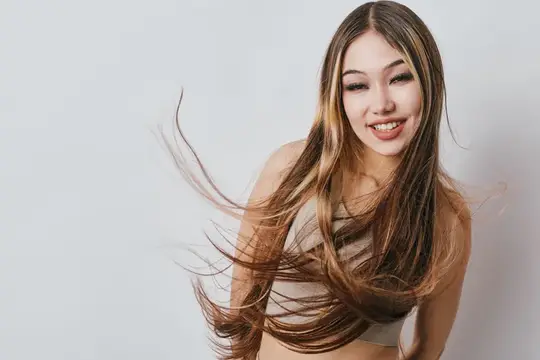Улыбающаяся азиатская девушка с развевающимися длинными волосами