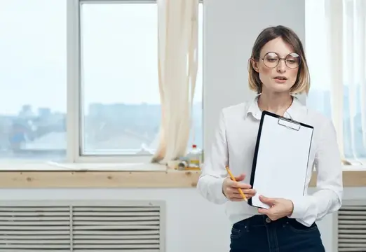 Молодая женщина в очках с планшетом у окна