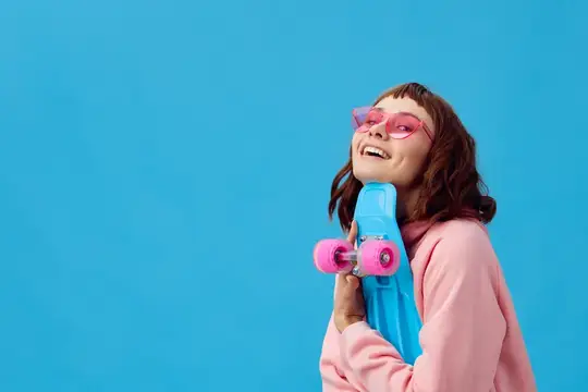 Улыбающаяся девушка в розовых очках с ярким скейтбордом на синем фоне